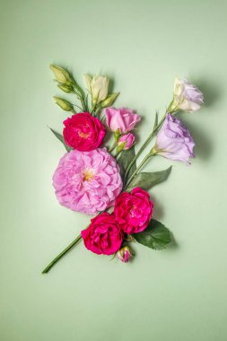 Yumuşak yeşil arka planda pembe güller ve lisianthus çiçekleri. Üst Manzara. Fotokopi alanı olan bahar ya da yaz çiçekleri. dikey resim