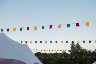 Mavi gökyüzünün arka planına karşı kumaş bayraklar ve ampullerden oluşan çelenk