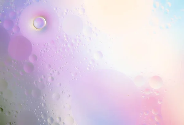 Abstract background in violet soft tones. Macro drops of oil on the surface of the water. Delicate cosmetic background for advertising products. Copy space