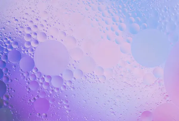 Suyun yüzeyinde güzel küçük yağ kabarcıkları. Reklam ürünleri için zarif kozmetik menekşe mavisi arka plan. Boşluğu kopyala 