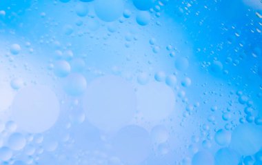 Suyun yüzeyinde güzel küçük yağ kabarcıkları. Reklam ürünleri için hassas mavi kozmetik arka plan.