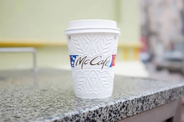 stock image Kyiv, Ukraine, November 2019, McDonald's. McCafe McDonald's disposable coffee cup with a white lid placed on a stone table in an outdoor setting on a blurred background