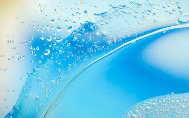 Baloncuklu ve damlacıklı mavi sıvının yakın çekimi soyut, ferahlatıcı ve temiz bir görünüm yaratıyor. Geçmişler, su temaları ve taze kavramlar için ideal.