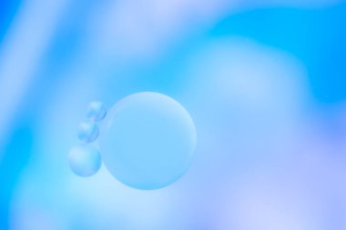 Mavi tonlarda odağını kaybetmiş. Güzel yağ baloncukları. Kozmetik ürünlerin reklamları için hassas bir arka plan. Suyun yüzeyine yağ damlalarının makro fotoğrafı.. 