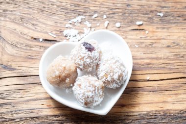 Laddu 'yu hindistancevizi parçacıkları içinde lamolina' dan kapatın, geleneksel Hint tatlıları beyaz bir tabakta ahşap bir arka planda. Bulanık ve seçici odaklanma