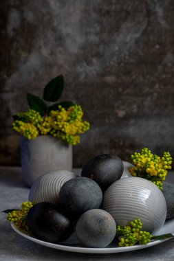 Değişik dokulu seramik küreler ve canlı sarı çiçeklerle tamamlanmış siyah paskalya yumurtalarının yer aldığı modern natürmort yaşam kompozisyonu