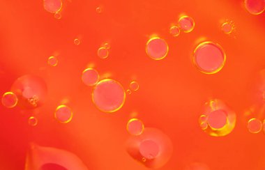 Kırmızı ve turuncu tonlarda yüzen yağ kabarcıkları içeren soyut bir arka plan. Yakın plan çekimlerde parlayan dairesel şekiller ve canlı bir sıcaklık gradyanı vurgulanıyor. Metin ve tasarımlar için alanı kopyala. 