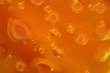 Turuncu tonlarda yüzen yağ kabarcıkları içeren soyut bir arka plan. Yakın plan çekimlerde parlayan dairesel şekiller ve canlı bir sıcaklık gradyanı vurgulanıyor. Metin ve tasarımlar için alanı kopyala. 