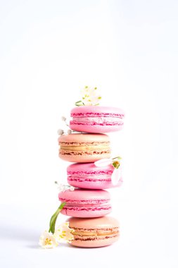 Beyaz arka planda pembe ve bej badem kurabiyeleri ve bahar çiçekleri, fotoğraf estetiği..