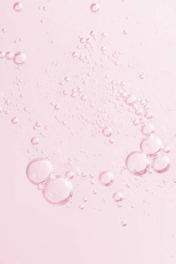 Hava kabarcıkları olan soyut bir arka plan, kozmetiğin dokusunu ve hafifliğini mükemmel bir şekilde yakalıyor. Pembenin pastel gölgeleri saflık ve tazelik hissi yaratır. konsept cilt bakım kozmetik çözeltisi.
