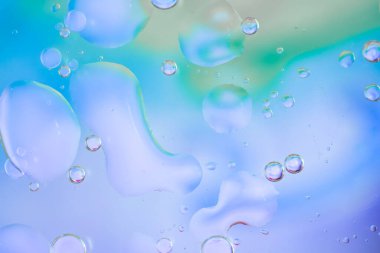 Suda yüzen yağ kabarcıkları olan renkli soyut bir arka plan. Mavi, pembe, sarı ve yeşil tonlarında yumuşak ve havadar bir etki yaratır. Renkli damlalar, sıvı doku, bulanık şekiller.. 
