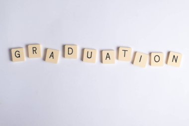 Kelime mezuniyeti, temiz beyaz arka planda tahta harf fayanslarından oluşuyor. Eğitim, okul ve kutlama temaları için ideal.