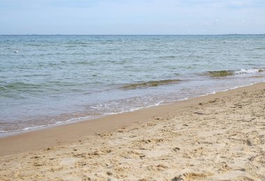 Sakin bir baltık denizi ve küçük dalgalarla sakin bir kumsal manzarası. Ufuk temiz ve bir sürü kopya alanı var. Doğal ışık kumu aydınlatır. Boşluğu kopyala 