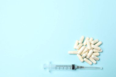 Mavi arka planda şırınga ve haplar