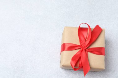 Gri arka planda kırmızı bir fiyonk olan mevcut kutu. Bir yay ile hediye