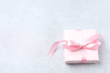 Beyaz arka planda pembe kurdeleli güzel bir hediye kutusu.