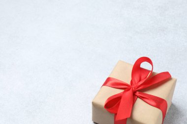 Kırmızı kurdeleli gri arka planda hediye kutusu. Metnin veya tasarımın için kopyalama alanı olan en üstteki görünüm.
