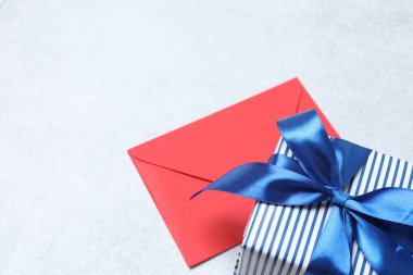 Kırmızı kurdeleli hediye kutusu ve beyaz arka planda yay