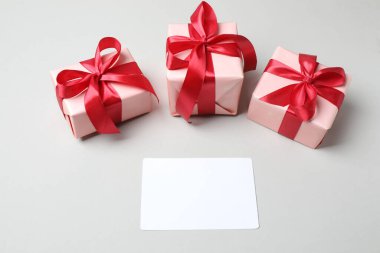 İçinde boş bir kart ve tahta bir masanın üstünde kırmızı kurdele olan hediye kutuları. Sevgililer Günü konsepti