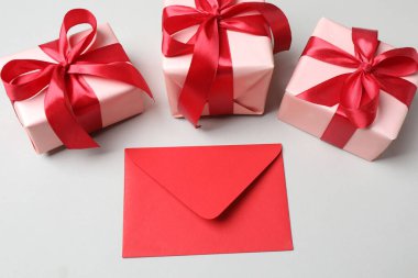 Beyaz arkaplanda kırmızı fiyonklu zarflar.