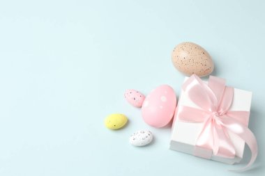 Paskalya tatili konsepti. Paskalya yumurtalarının ve pembe pastel arka planda hediye kutusunun üst görüntüsü metin için fotokopi alanı ile birlikte. düz yatış, üst görünüm,