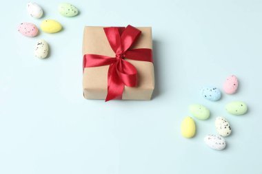 Paskalya bayramı kompozisyonu, yuvadaki paskalya yumurtaları ve pembe arka planda bir hediye kutusu. Üst görünüm, düz uzanma.