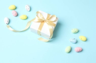 Hediye kutusu ve mavi arka planda renkli yumurtaları olan paskalya kompozisyonu. Paskalya konsepti. düz üst görünüm