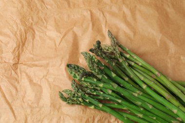 Kahverengi kağıttan arka planda taze yeşil kuşkonmaz.