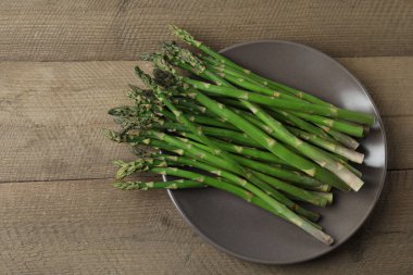 Tahta arka planda taze yeşil kuşkonmaz.