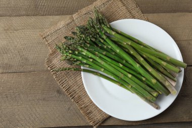 Tahta arka planda taze yeşil kuşkonmaz.