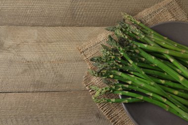 Tahta arka planda taze yeşil kuşkonmaz.