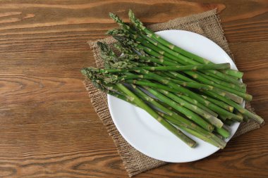 Tahta arka planda taze yeşil kuşkonmaz.