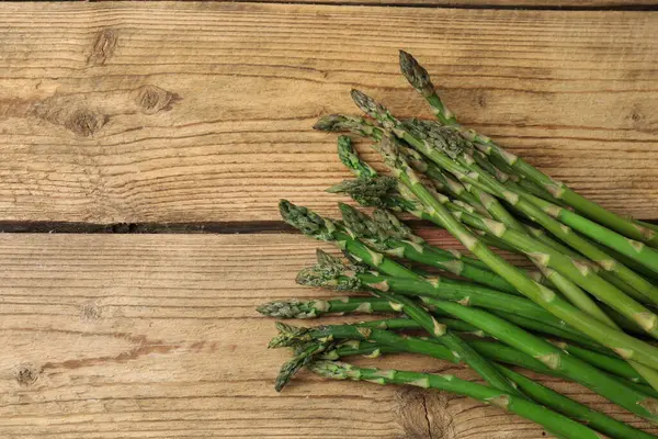 Tahta arka planda taze yeşil kuşkonmaz.