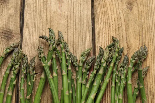 Tahta arka planda taze yeşil kuşkonmaz.