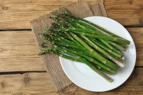 Tahta arka planda taze yeşil kuşkonmaz.
