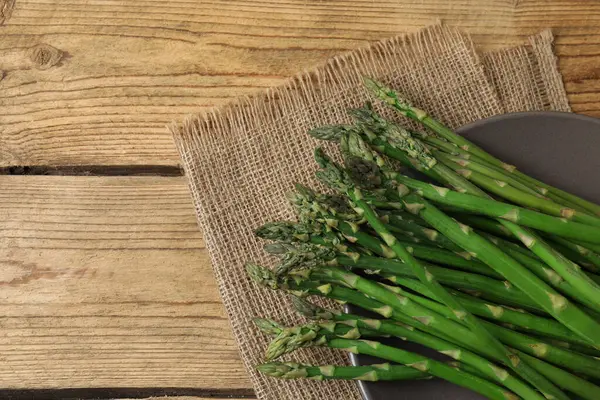 Tahta arka planda taze yeşil kuşkonmaz.