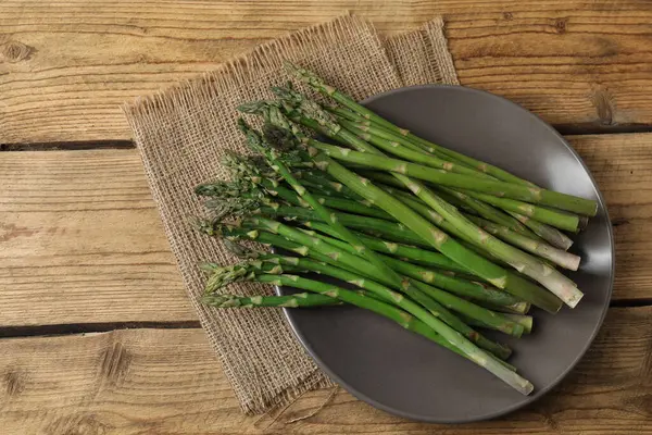 Tahta arka planda taze yeşil kuşkonmaz.