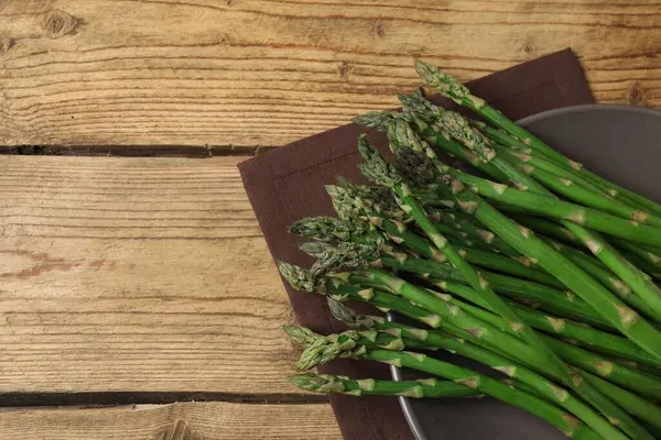 Tahta arka planda taze yeşil kuşkonmaz.