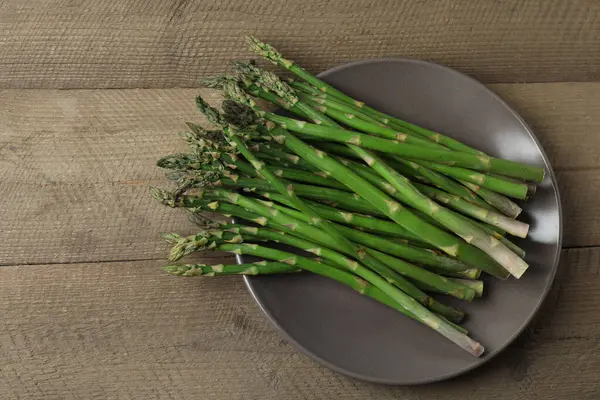 Tahta arka planda taze yeşil kuşkonmaz.