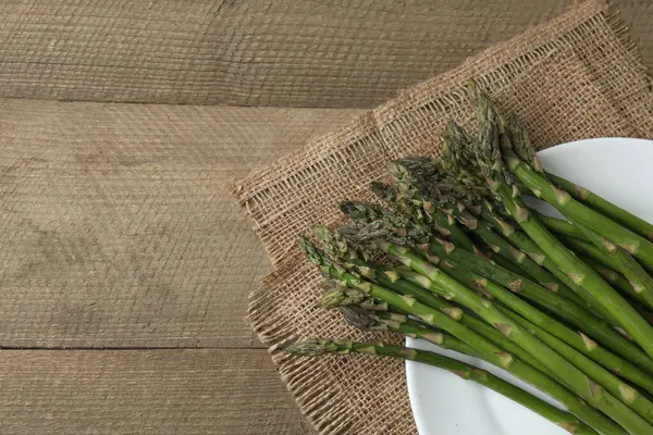 Tahta arka planda taze yeşil kuşkonmaz.