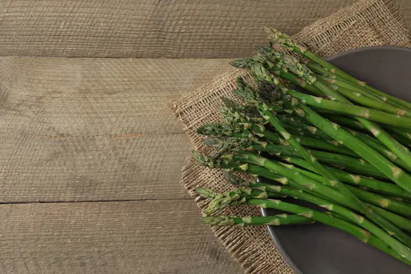 Tahta arka planda taze yeşil kuşkonmaz.