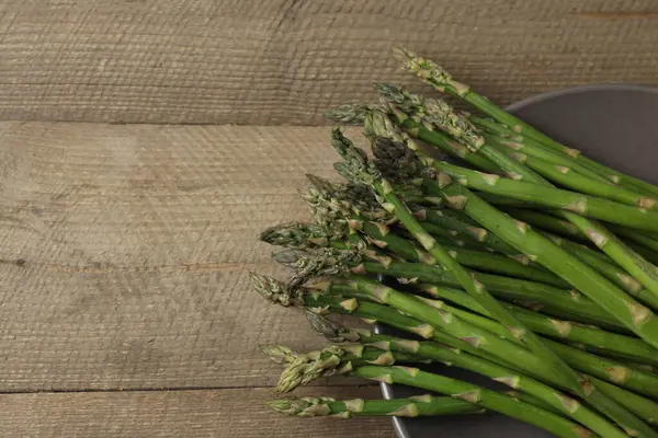 Tahta arka planda taze yeşil kuşkonmaz.