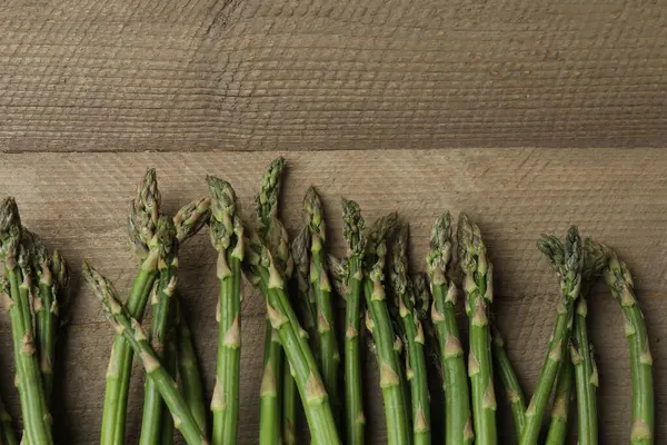 Tahta arka planda taze yeşil kuşkonmaz.