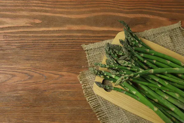 Tahta arka planda taze yeşil kuşkonmaz.