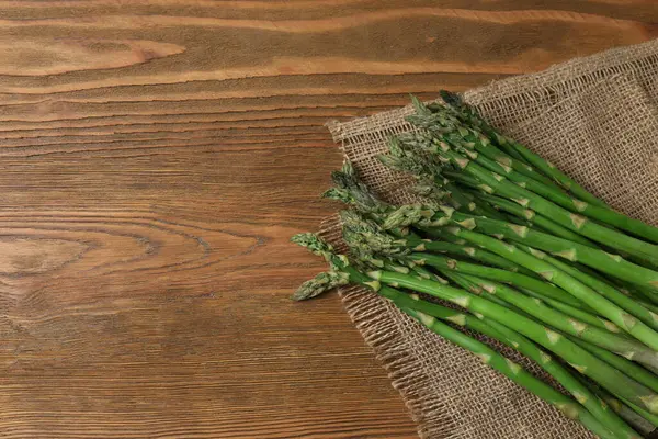 Tahta arka planda taze yeşil kuşkonmaz.