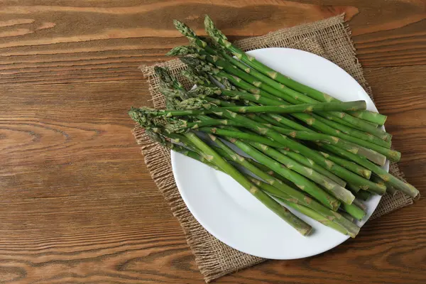 Tahta arka planda taze yeşil kuşkonmaz.