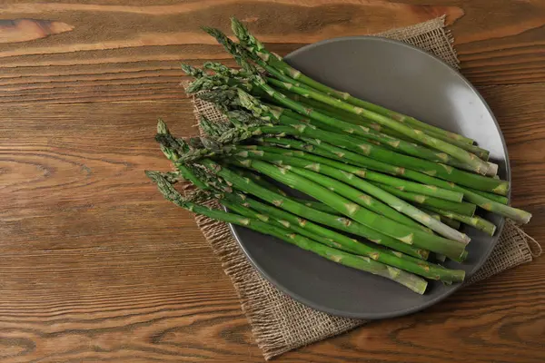 Tahta arka planda taze yeşil kuşkonmaz.