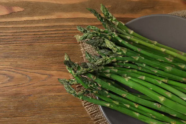 Tahta arka planda taze yeşil kuşkonmaz.