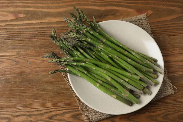 Tahta arka planda taze yeşil kuşkonmaz.