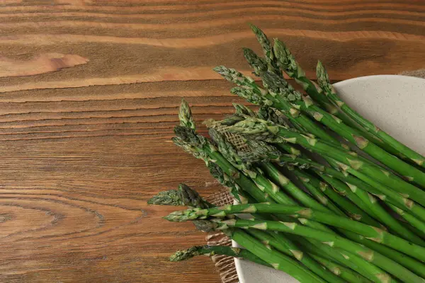 Tahta arka planda taze yeşil kuşkonmaz.